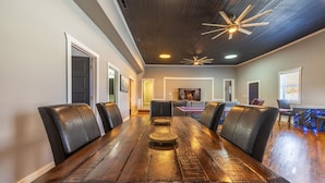 A spacious dining area with a long wooden table and leather chairs, a ceiling fan, and recessed lighting. - The Grange (In the Heart of the Hocking Hills) (Laurelville)