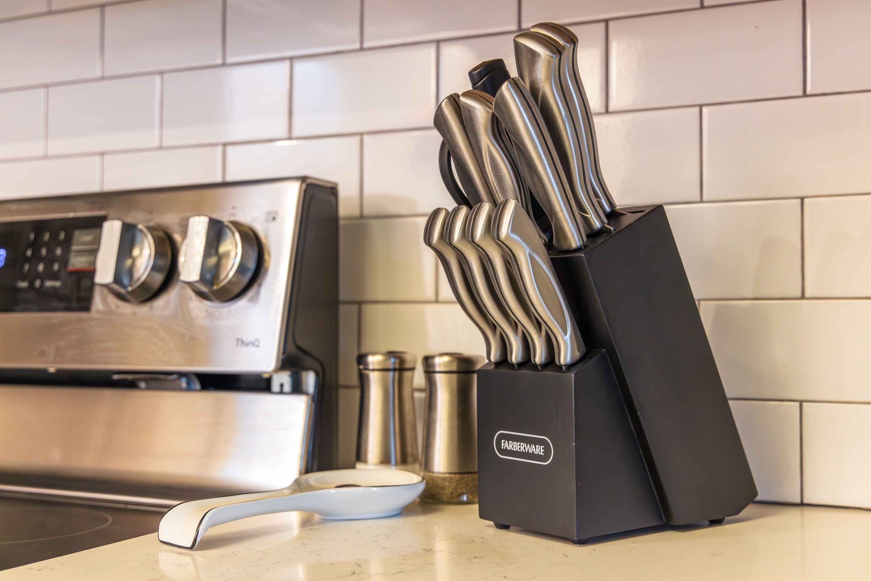 A kitchen counter with a modern stove, a knife block, and a salt shaker.