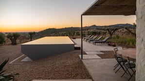 Un espace extérieur aménagé avec une longue table et des chaises, une pergola et une vue sur les collines.