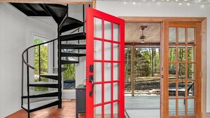 A modern interior with a spiral staircase, a red door, and a view of the outdoors.