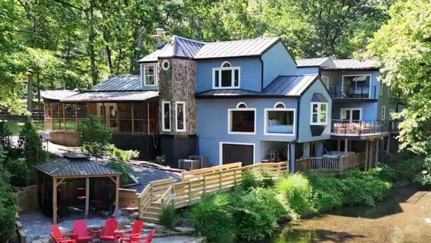 A lakeside cabin with a dock, outdoor seating, and a covered area.