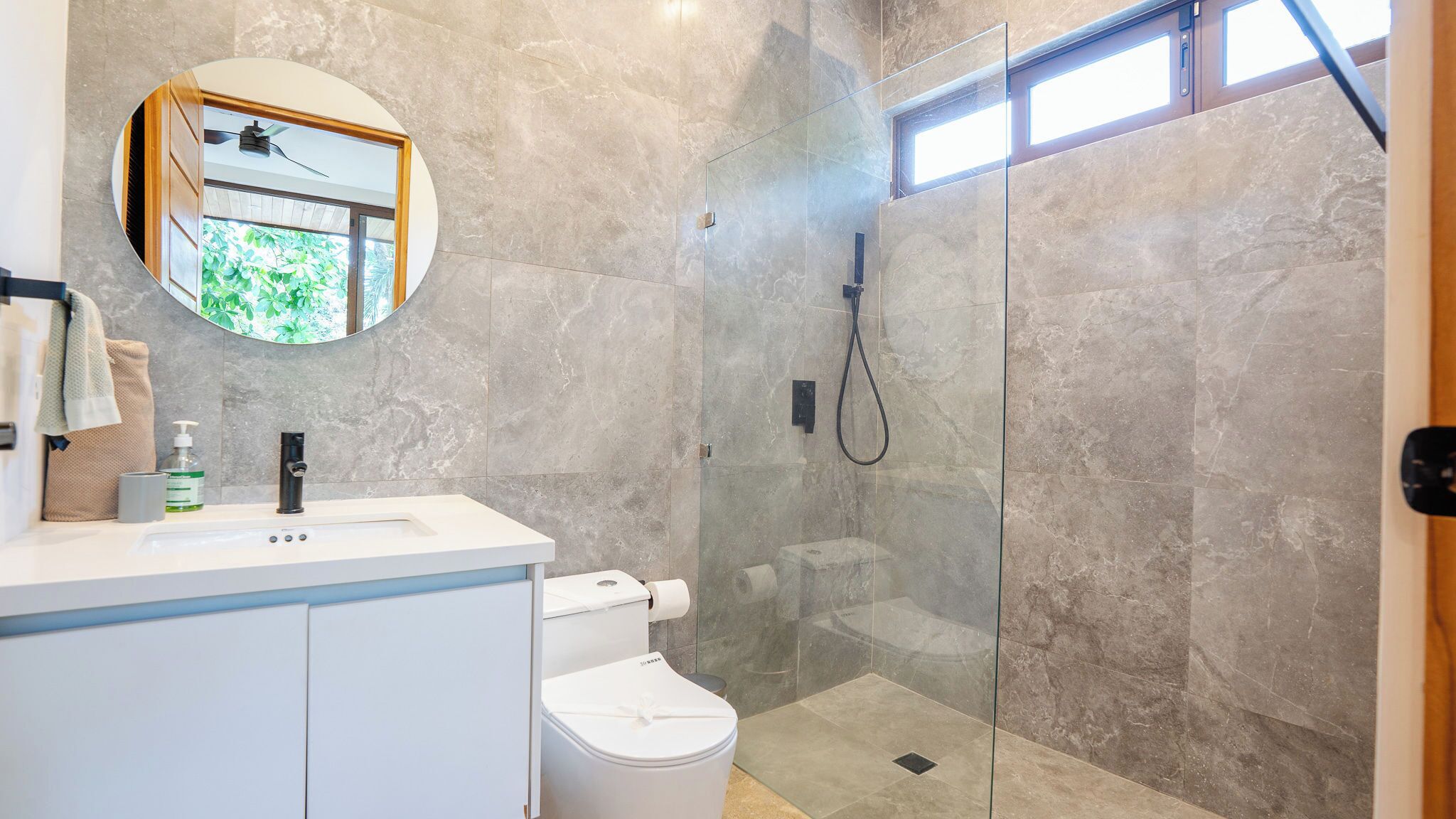 Un baño moderno con ducha envuelta en vidrio, un lavabo blanco y un inodoro.