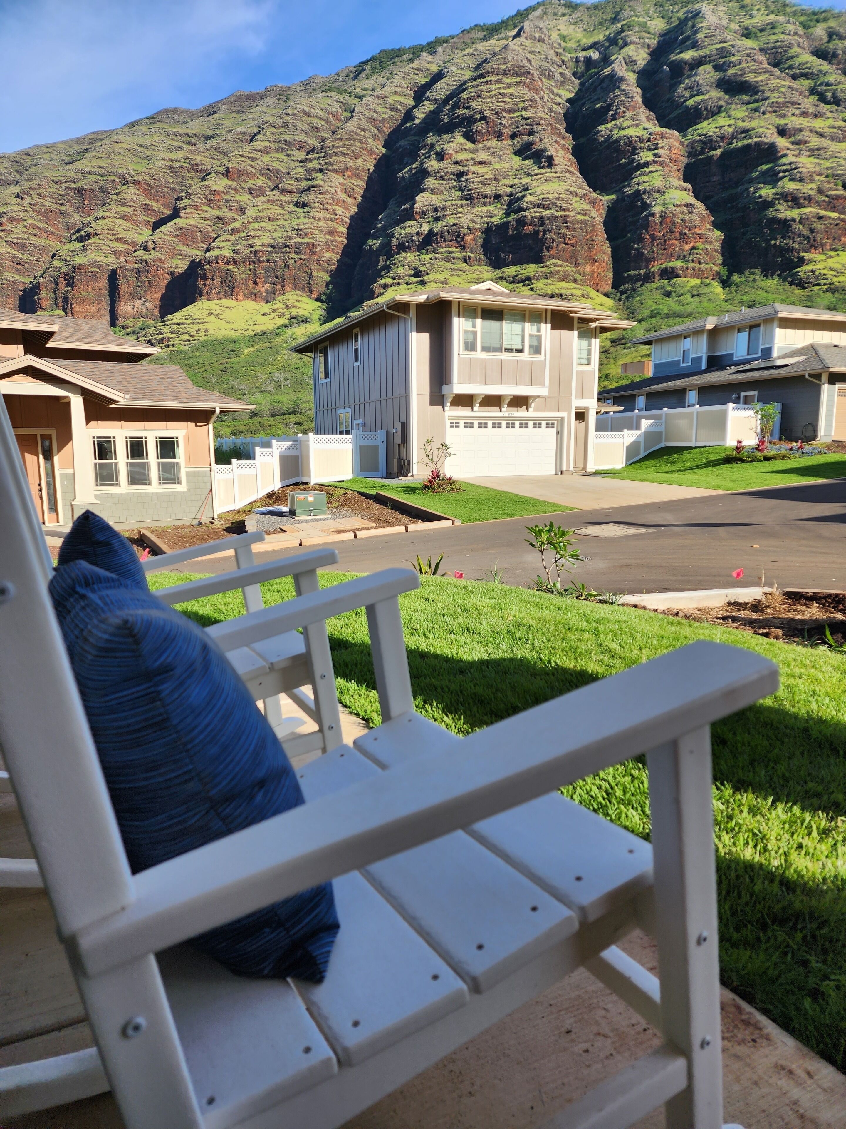 A residential area with houses, a bench, and a mountainous backdrop.