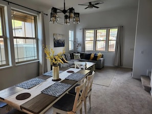 Relax in this open-plan living and dining area with a dining table, sofas, and large windows offering a view of the outside.
