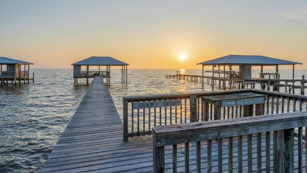 A wooden pier leading to three covered structures with benches, over water. - Charming Bayfront Getaway - Private Pier (Fairhope)