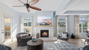 A spacious living room with a fireplace, comfortable seating, and a large TV. - Oversized home w/ Heated Pool - mins from beach! (St. Augustine)