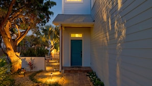A house with a blue door, a pathway leading to the entrance, and a small garden with various plants and a tree. - Oversized home w/ Heated Pool - mins from beach! (St. Augustine)