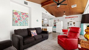 Ein modernes Wohnzimmer mit einem schwarzen Sofa, einem roten Sessel und einem farbenfrohen floralen Gemälde an der Wand.