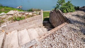 Eine Betontreppe führt zu einem hölzernen Steg über einem ruhigen See.