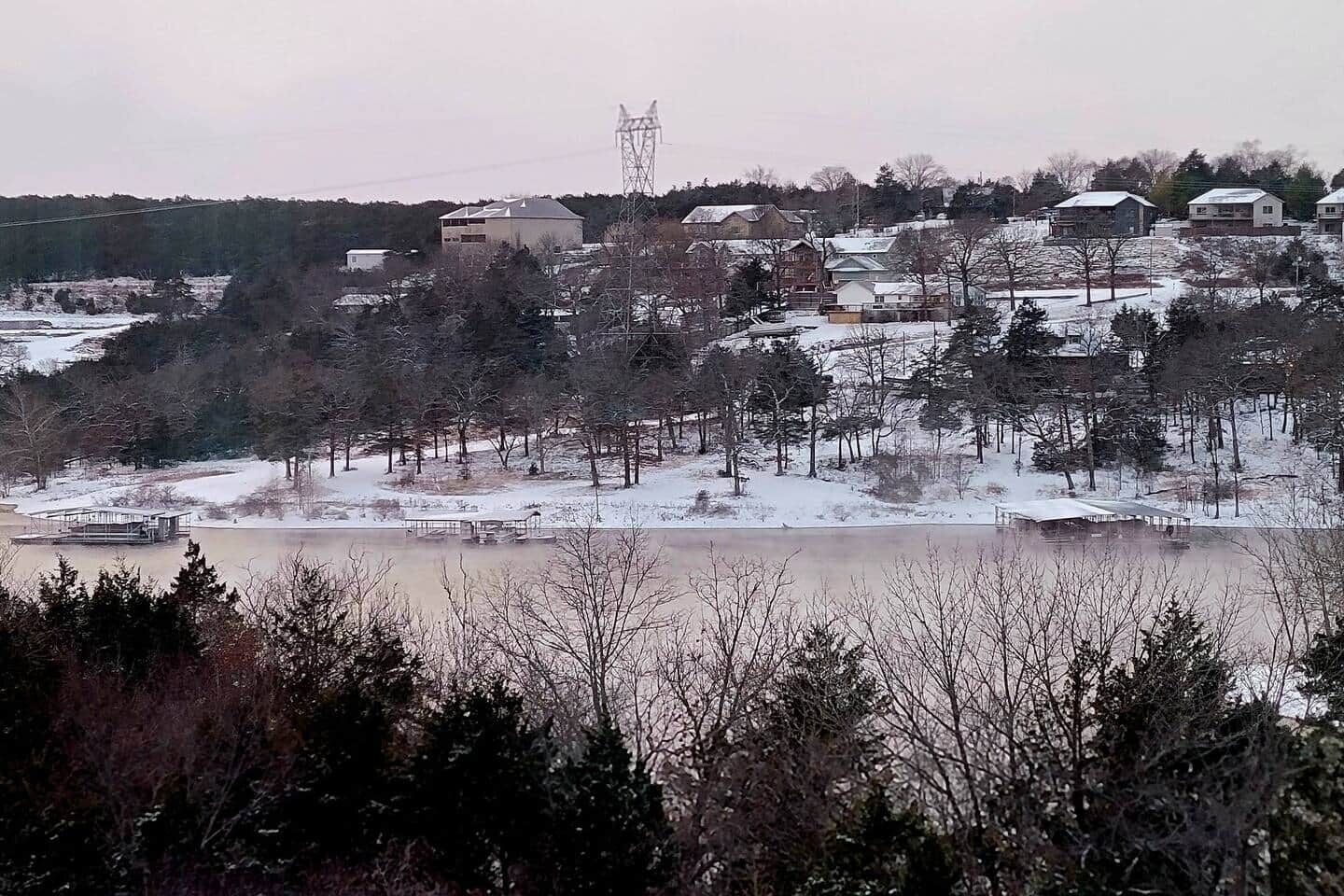 A residential area with houses, a body of water, and a power line tower.