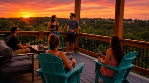 A group of people on a wooden deck with chairs and tables, overlooking a forested landscape. - Modern Luxury 5BR 4BA with Heated Pool and EV Charge (Branson)