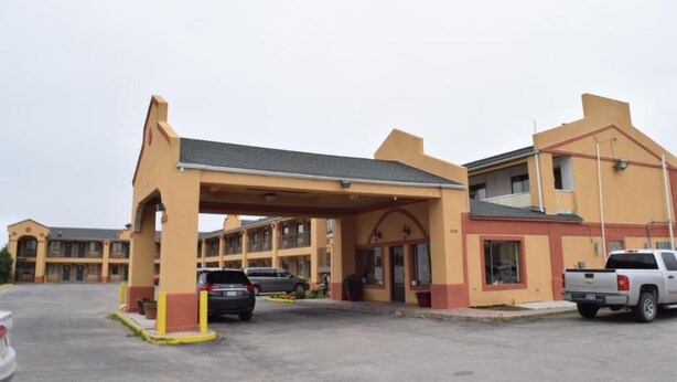 A motel with a covered parking area, multiple rooms, and a small commercial space. - Deluxe Inn By Capital O Odessa I-20 (Odessa)