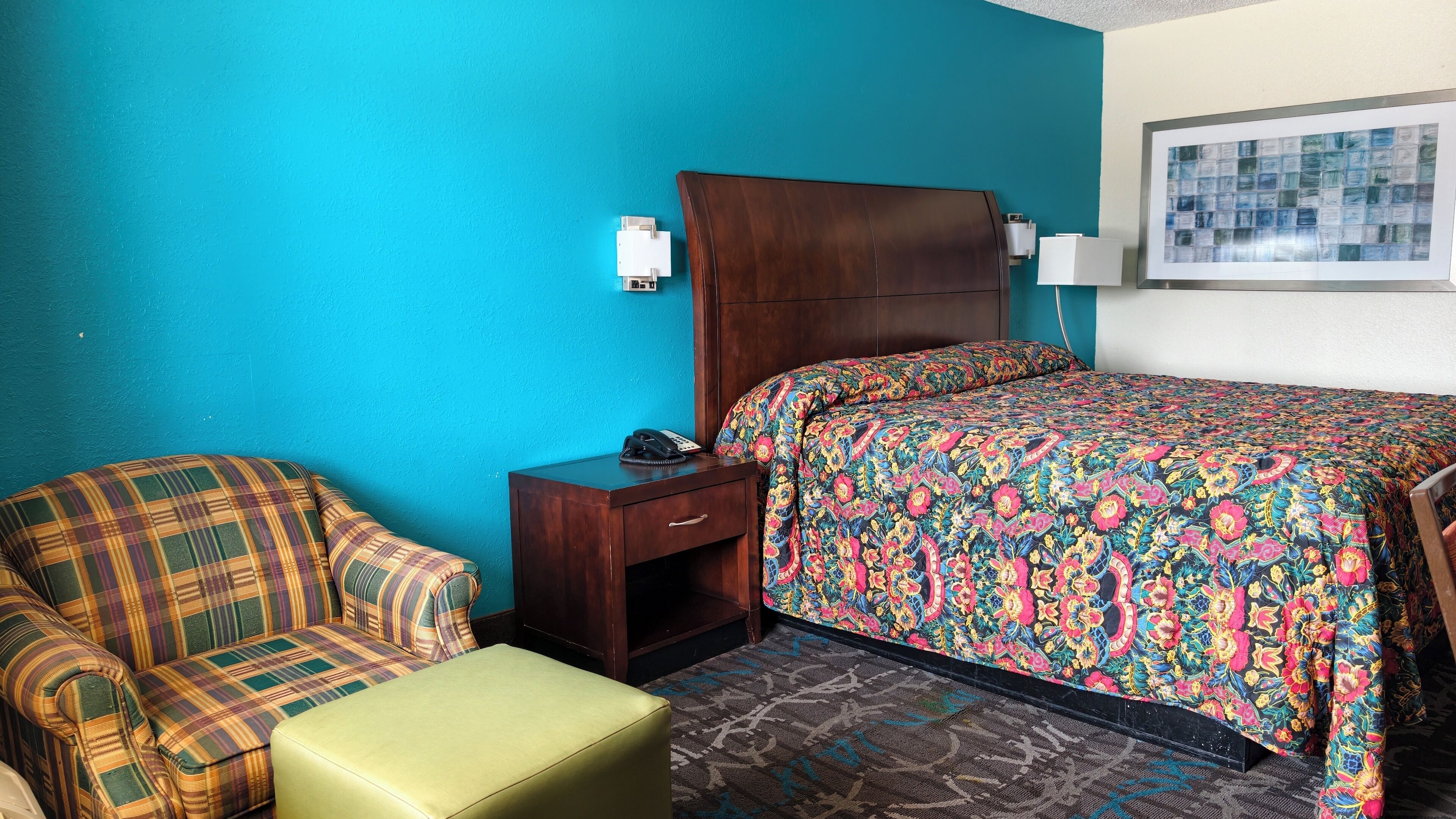 Ein Hotelzimmer mit einem Bett, einem Sessel, einem Nachttisch und einem kleinen Tisch.