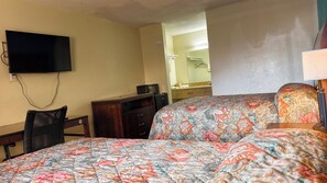 A hotel room with two beds, a desk, a television, and a microwave. - Deluxe Inn By Capital O Odessa I-20 (Odessa)