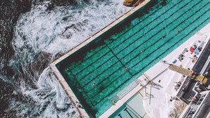 Vista aérea de una piscina junto a una costa rocosa con aguas transparentes.