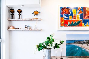 A room with a beach view, a framed abstract painting, and a vase with flowers. - Aqua Vista Getaway - Walk to Bondi Beach w Parking (Bondi Beach)