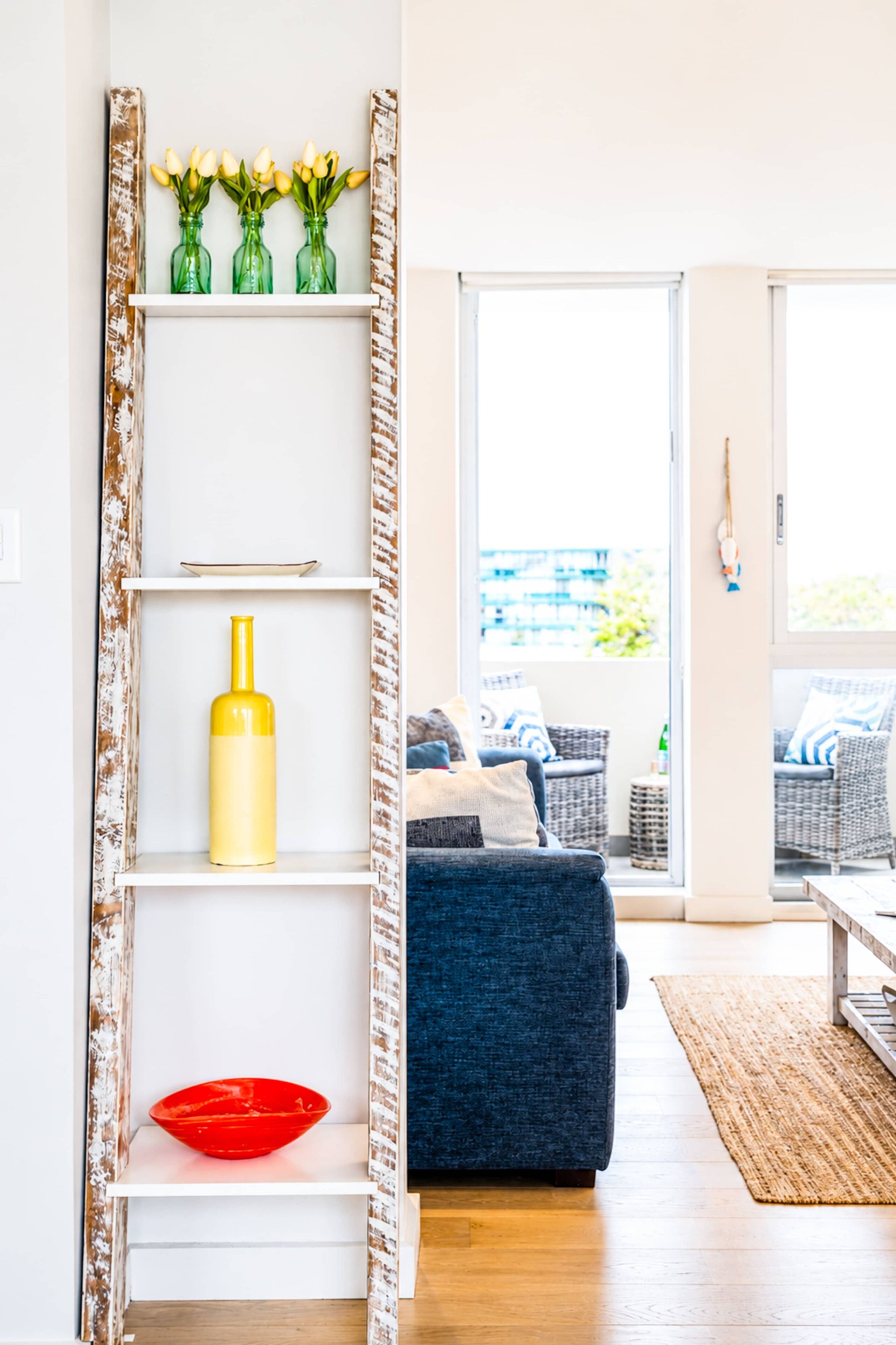A living room with a white shelf, a blue sofa, and a red bowl.