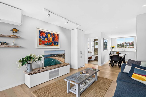 A modern living room with a flat-screen TV, a coffee table, and a sofa.