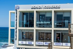 Un edificio de varios pisos con señalización que indica 'Bondi Icebergs' y 'escultura junto al mar'.