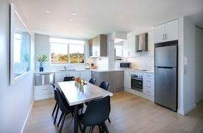 A modern kitchen with white cabinets, stainless steel appliances, and a dining area with a table and chairs.