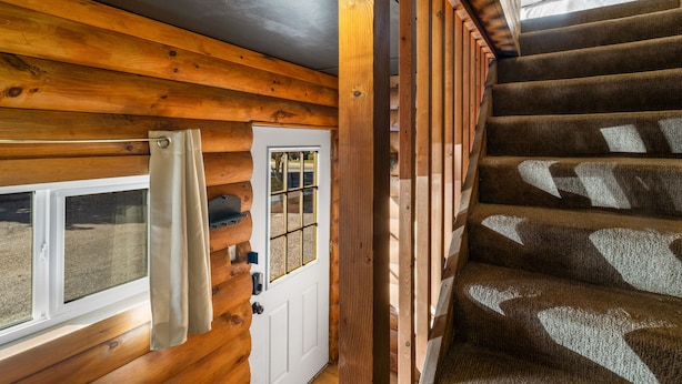 A wooden staircase with a handrail, a door with a window, and a curtain. - Experience comfort at The Bucking Moose (#02) The Loft, just 1 minute from Yellowstone! (West Yellowstone)