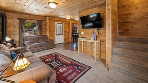 A cozy cabin interior with a wooden interior, a television mounted on the wall, a fireplace, and a comfortable seating area. - Stay at The Bucking Moose (#10) Cowboy Cabin, 2 bedroom cabin just 1 minute from Yellowstone (West Yellowstone)