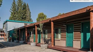 Une rangée de chalets de style rustique, avec des portes vertes et des balustrades en bois.