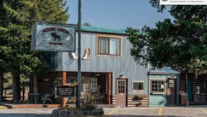 A rustic building with a sign reading "Moose Creek Cabins." There is a sign outside requesting visitors to check in at the front. - The Gopher Queen Room at The Bucking Moose, just 1 minute from Yellowstone in West Yellowstone. (West Yellowstone)