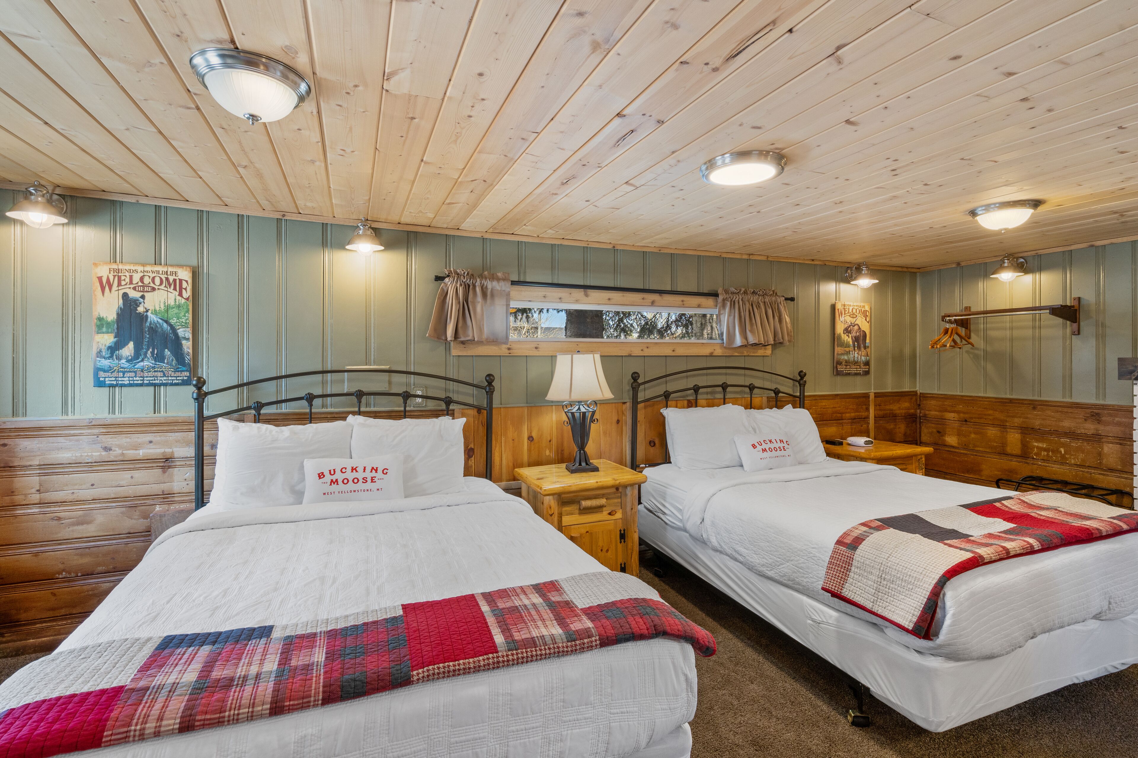 A room with two beds, wooden walls, and a ceiling with wooden beams.