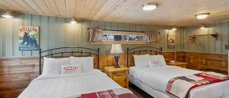 A room with two beds, wooden walls, and a ceiling with wooden beams.
