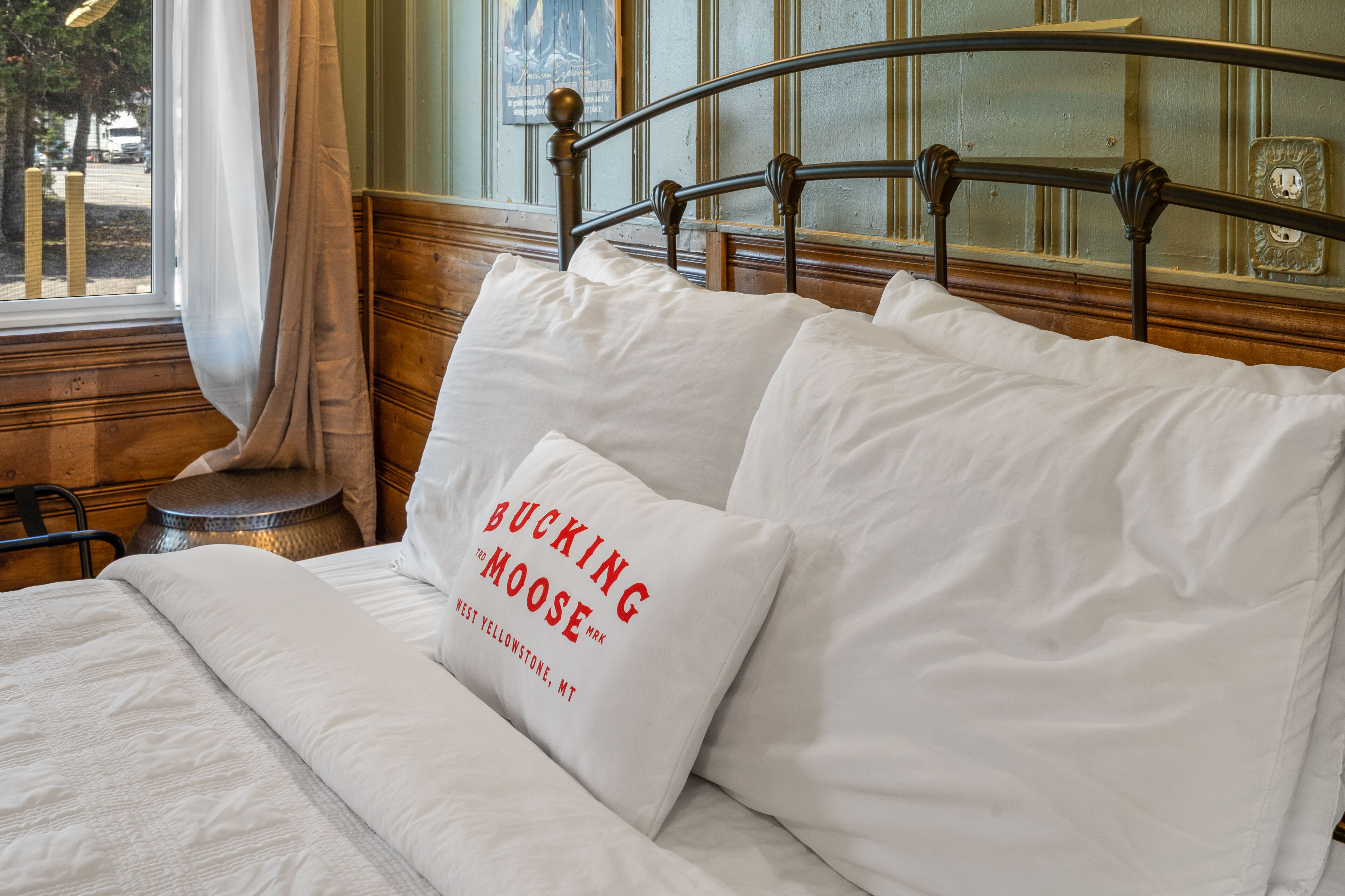 Un lit avec du linge de lit blanc et un oreiller orné d’un motif textuel.