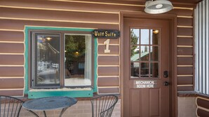 A rustic building exterior with a sign reading "Wolf Suite 1" and a door labeled "Mechanical Room Here".