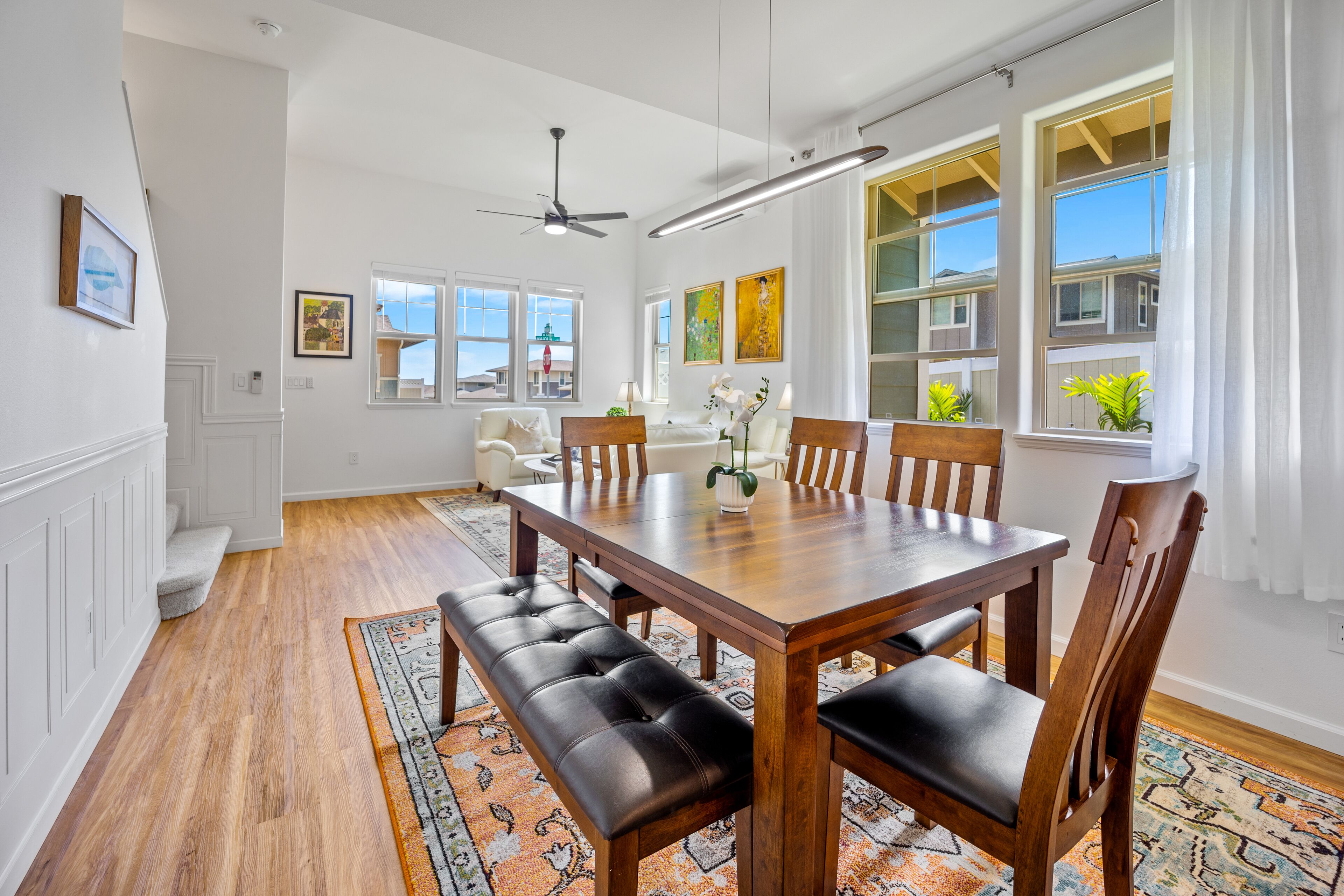 A dining area with a wooden table, leather benches, and a patterned rug.