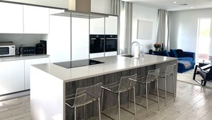 A modern kitchen with a central island, bar stools, a built-in oven, and a microwave. - Modern Luxury Townhome in Nassau - steps to the beach! (Nassau)