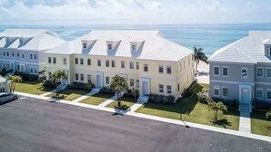 A row of coastal buildings with a flat roof, a paved driveway, and a view of the ocean. - Modern Luxury Townhome in Nassau - steps to the beach! (Nassau)