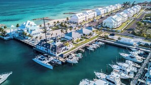 An aerial view of a marina with boats docked, a row of white buildings, and a clear blue sky. - Modern Luxury Townhome in Nassau - steps to the beach! (Nassau)