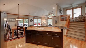 Una cocina amplia con armarios de madera oscura, encimera de granito y comedor con mesa y sillas de madera.