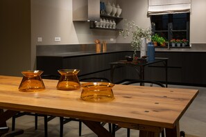 Une cuisine moderne avec une table à manger en bois, un four encastré et une fenêtre agrémentée de plantes en pot.