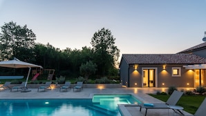 Un área de piscina exterior moderna con sillones de descanso y una estructura de juegos para niños.