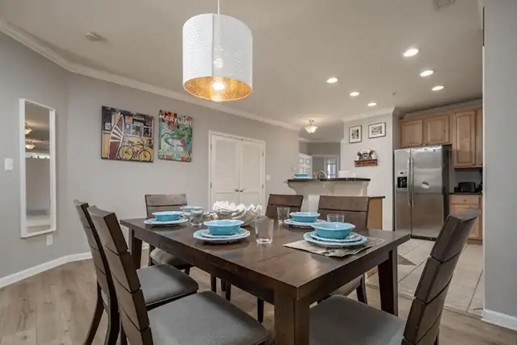 A dining area with a wooden table set for four, surrounded by chairs.