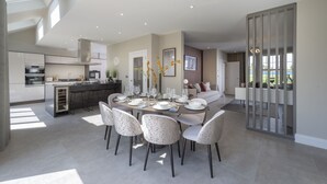 Una cocina moderna con una isla central, un área de comedor con una mesa redonda y sillas, y vistas al exterior.