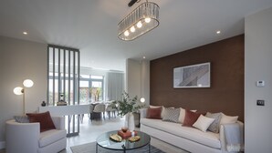 Una sala de estar moderna con un sofá blanco, una mesa de centro de cristal y una araña.