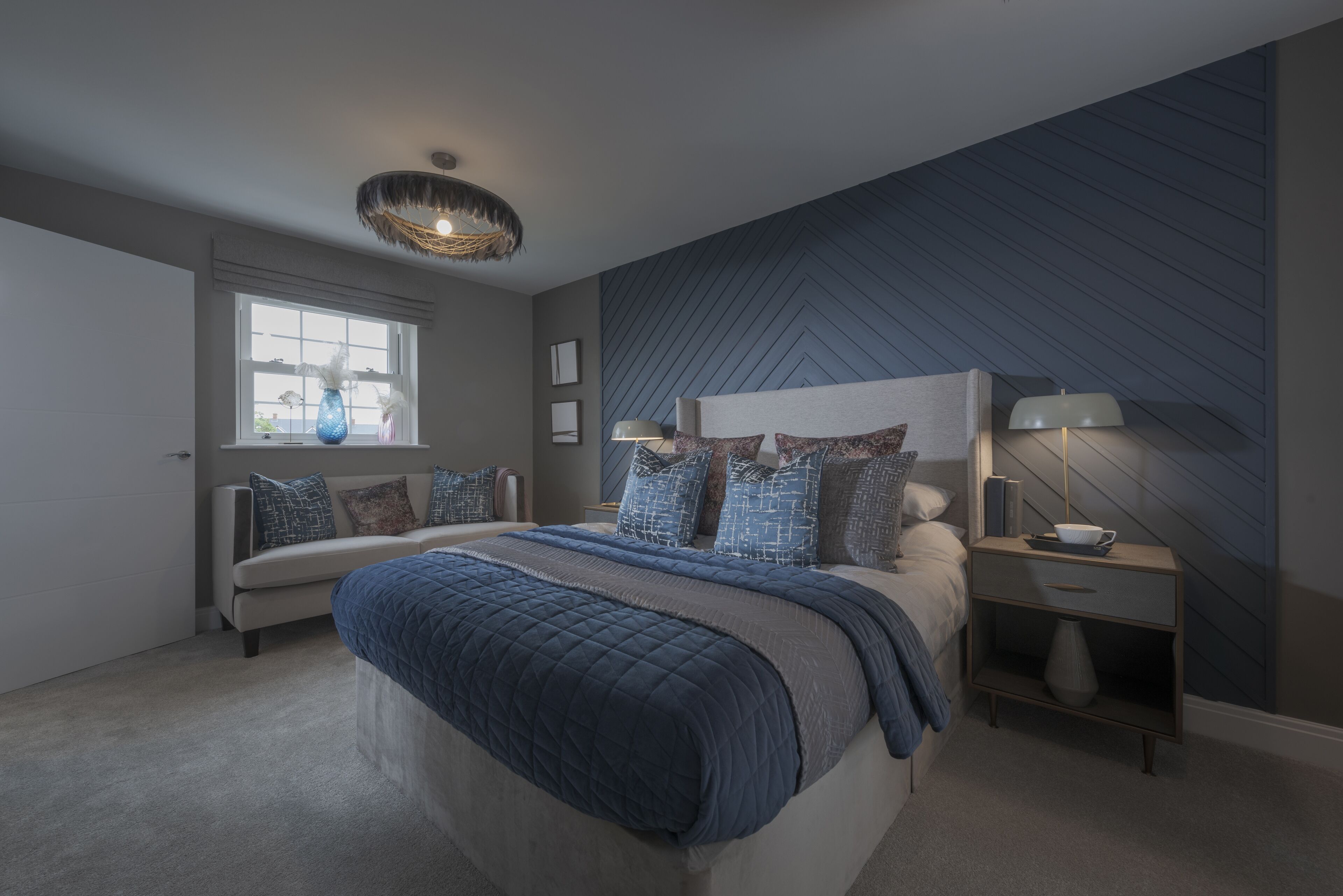 Een moderne slaapkamer met een groot bed, een nachtkastje, een lamp en een raam met zonwering.