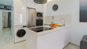 A modern kitchen with stainless steel appliances, a built-in oven, microwave, and a washing machine.
