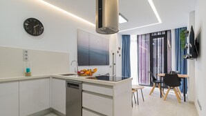 A modern kitchen with a dishwasher, a sink, and a fruit bowl. There is a dining area with a table and chairs.