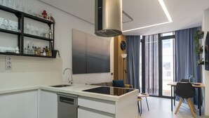 A modern kitchen with a dishwasher, a built-in oven, and a dining area with a table and chairs.