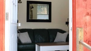 A living room with a green sofa, a white coffee table, and a mirror on the wall. - Guest House 10 Min to Smugglers! (Cambridge)