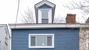 Ein blaues, zweistöckiges Haus mit weißer Tür, einer kleinen Veranda und der Hausnummer 3226 an der Tür.