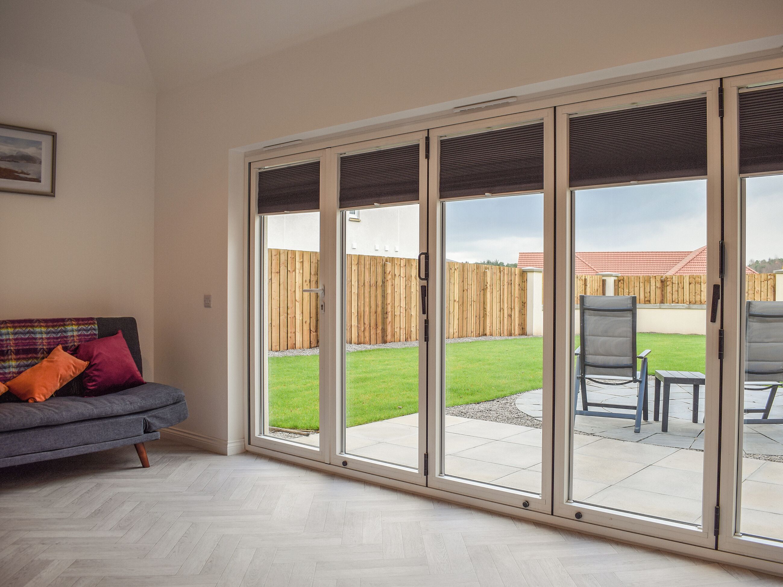 Une pièce dotée d’une porte-fenêtre coulissante donnant sur un patio, lequel est agrémenté d’une clôture en bois, d’une pelouse et de mobilier d’extérieur.