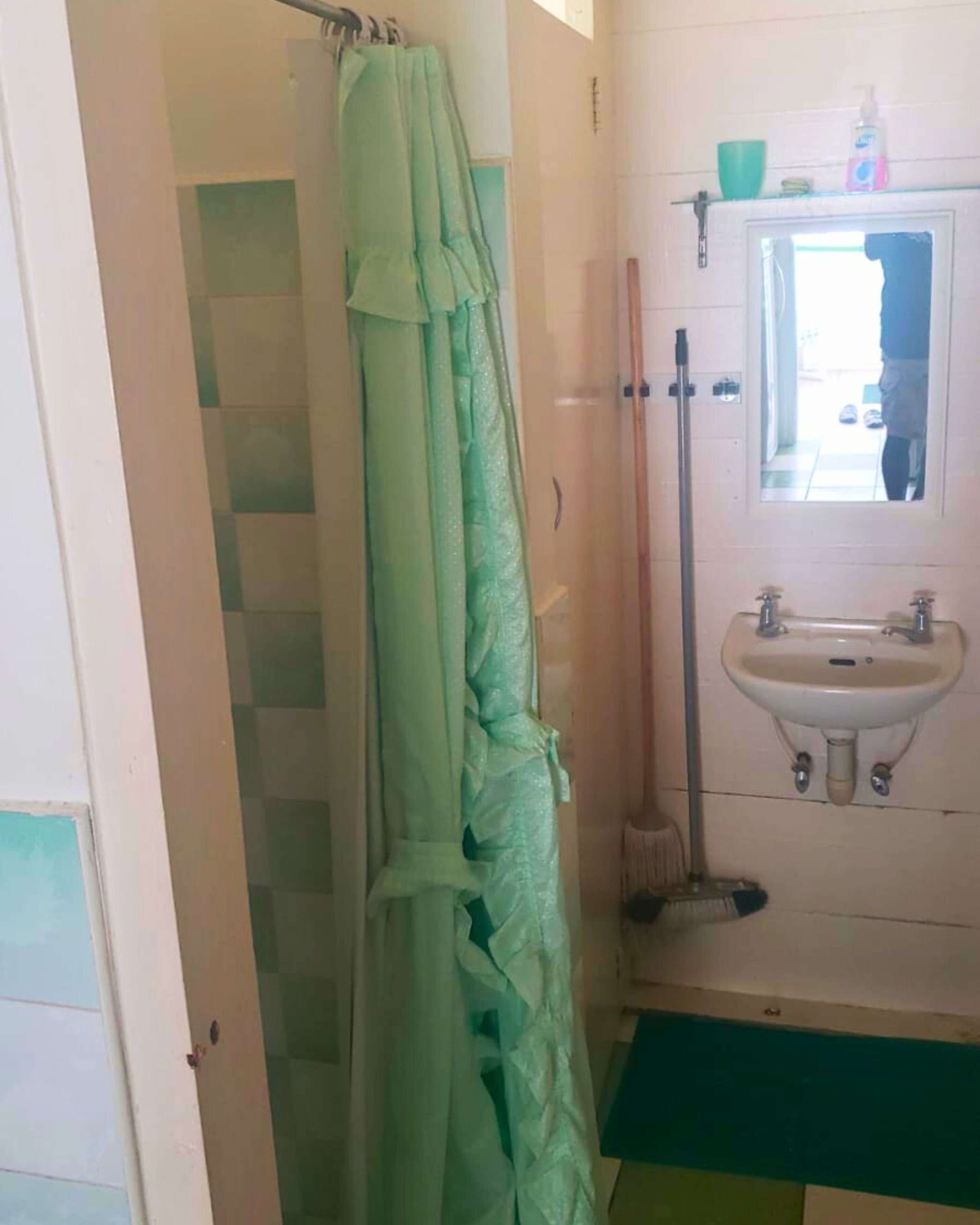 A bathroom with a shower curtain, a sink, and a mirror.